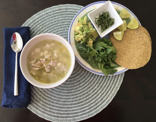 Green chicken pozole with condiment plate.